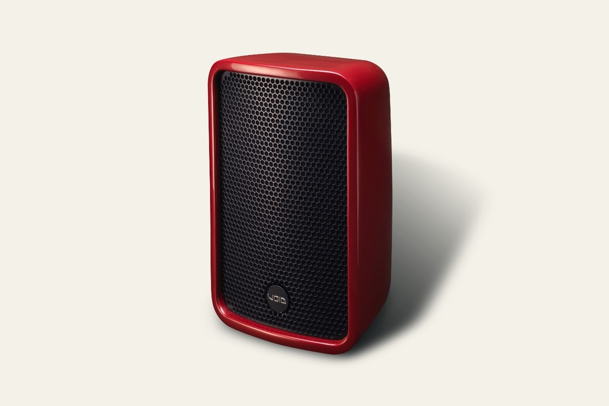 Enceinte rouge à grille noire vue de trois quarts sur fond crème