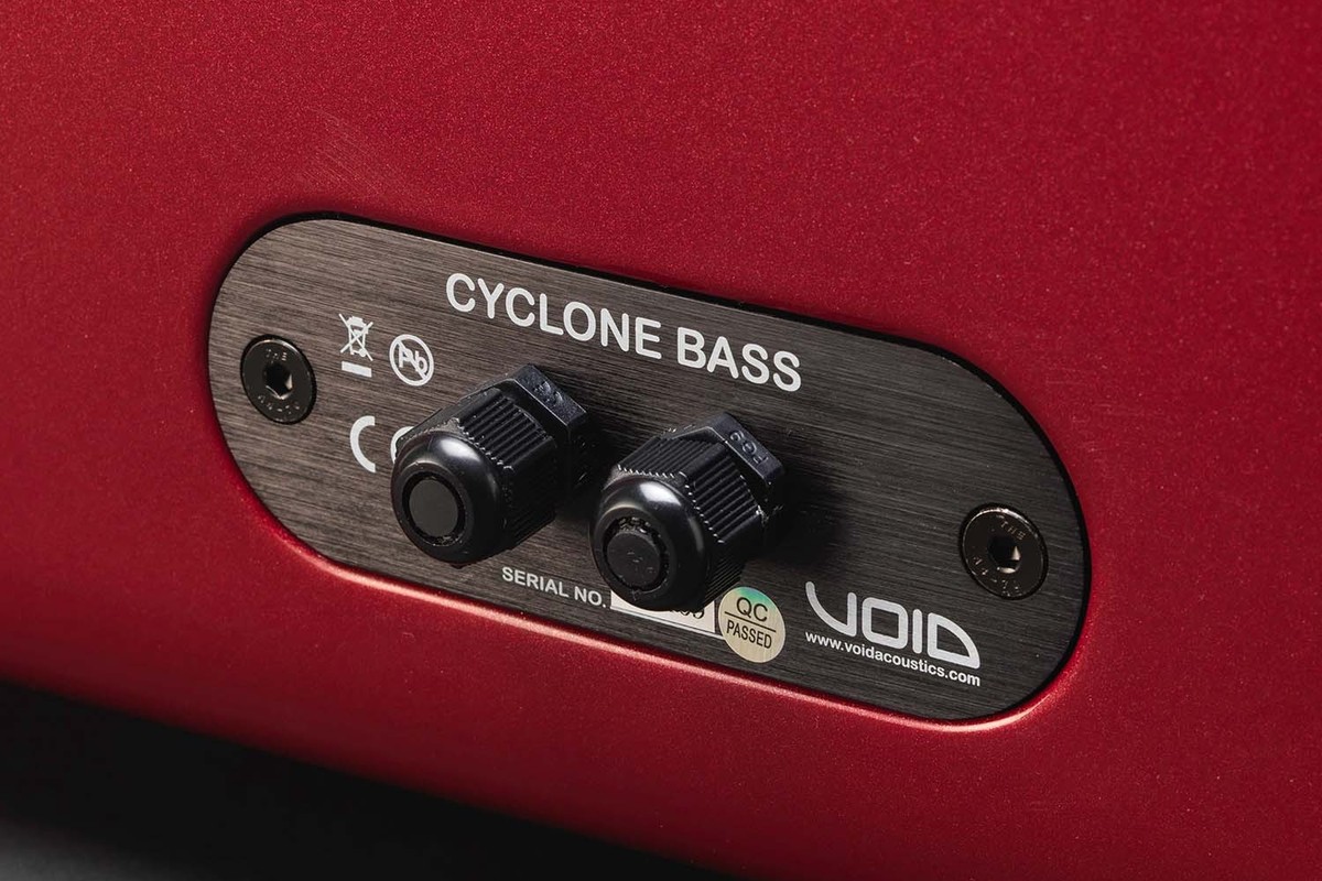 Face arrière d'un caisson de basses rouge avec ses deux presse-étoupes et sa plaque signalétique