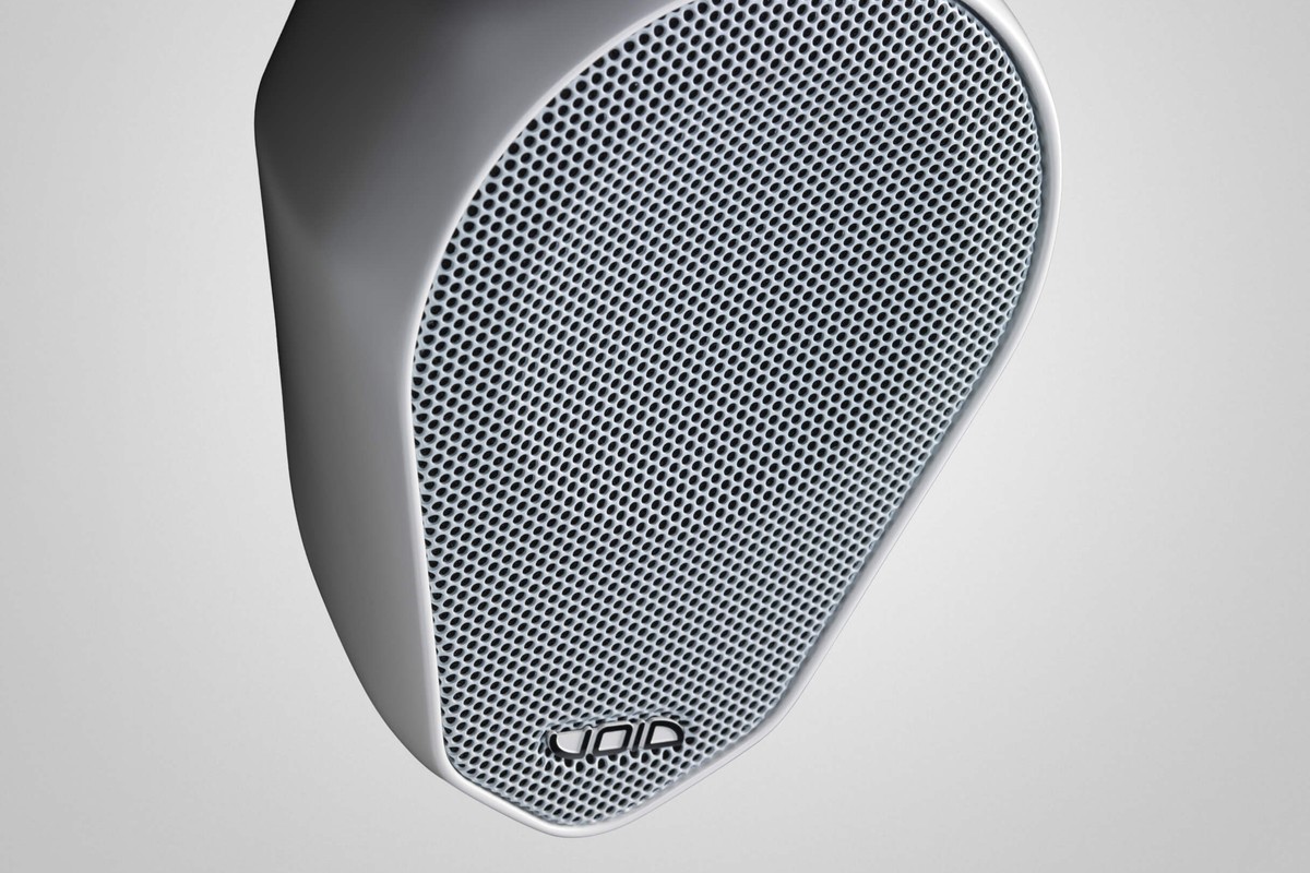 Enceinte blanche vue de trois quarts, grille perforée blanche et boîtier galbé