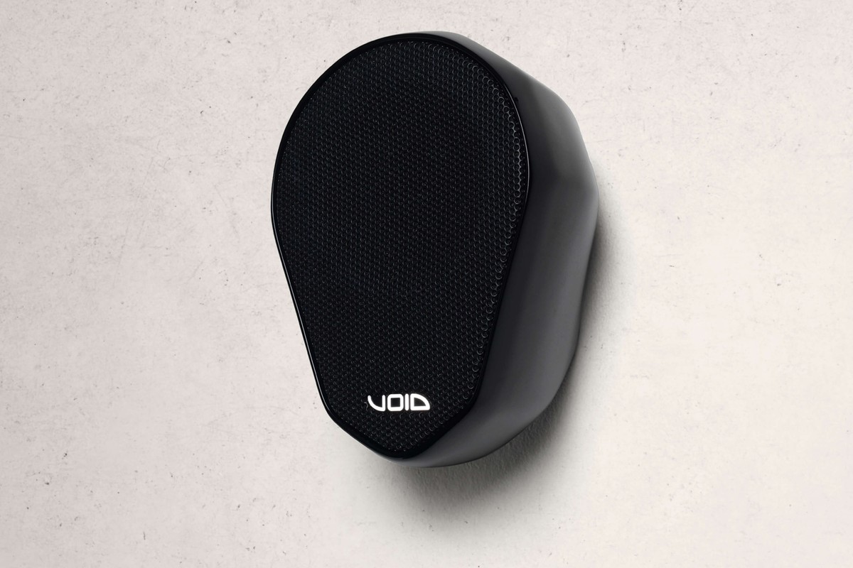 Enceinte noire fixée sur un mur de béton clair