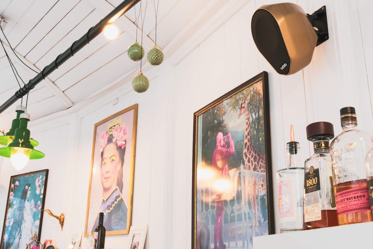 Enceinte à finition cuivrée fixée par son support au mur d'un bar