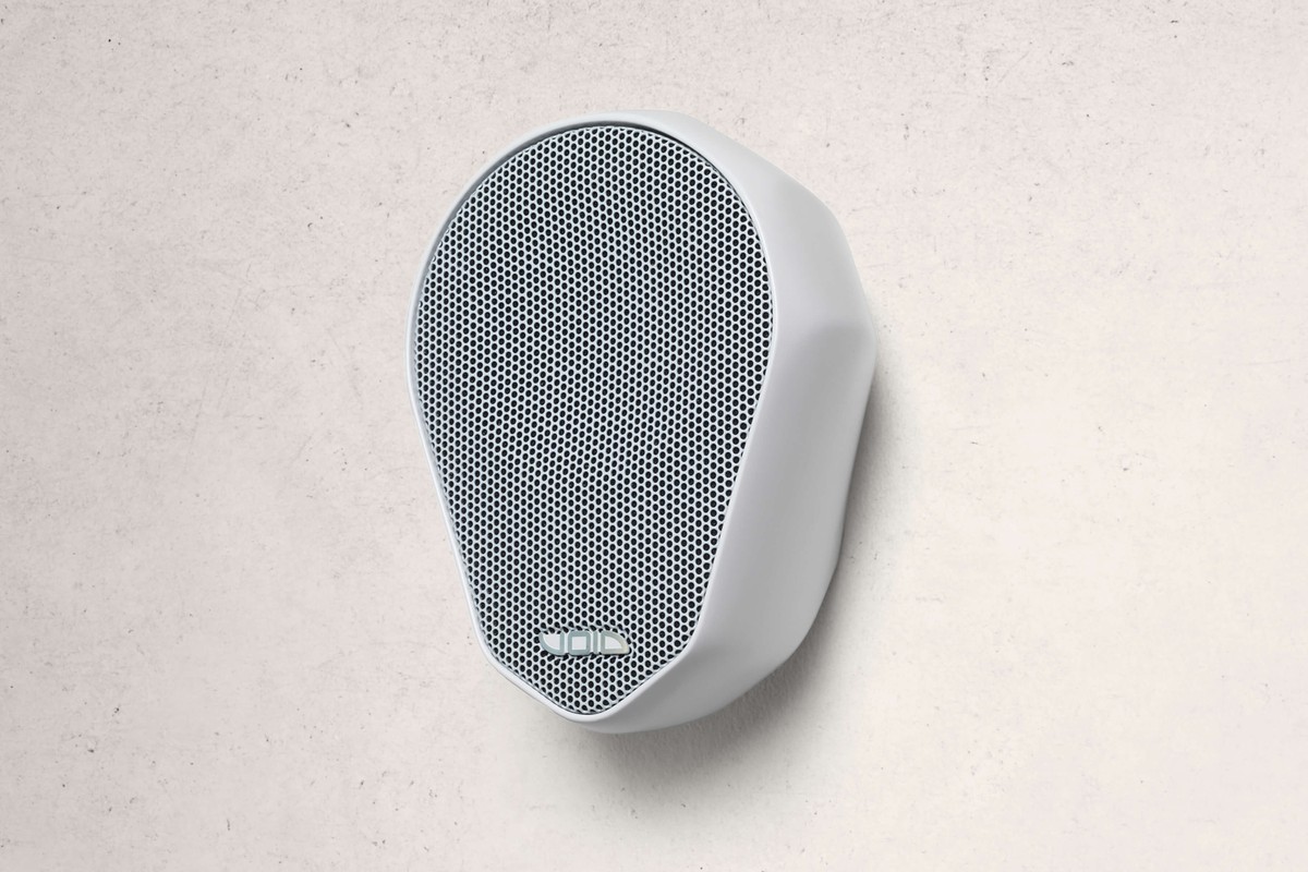 Enceinte blanche à grille blanche fixée sur un mur en béton clair