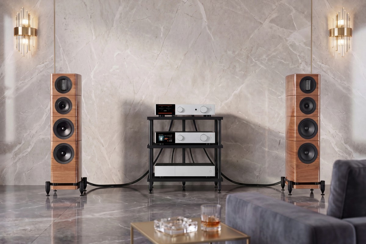 Two light walnut towers on either side of an amplifier rack, in front of a marble wall