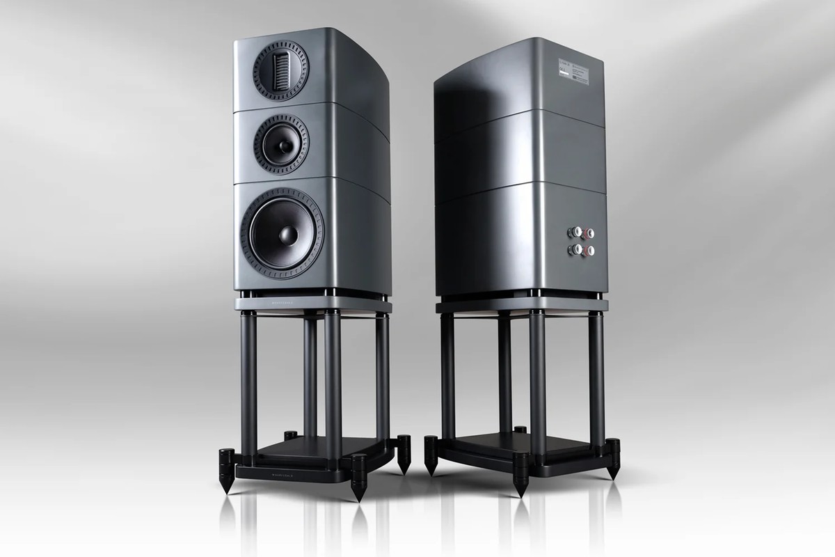 Two grey speakers on stands, one from the front with its three drivers, the other from behind with its terminals