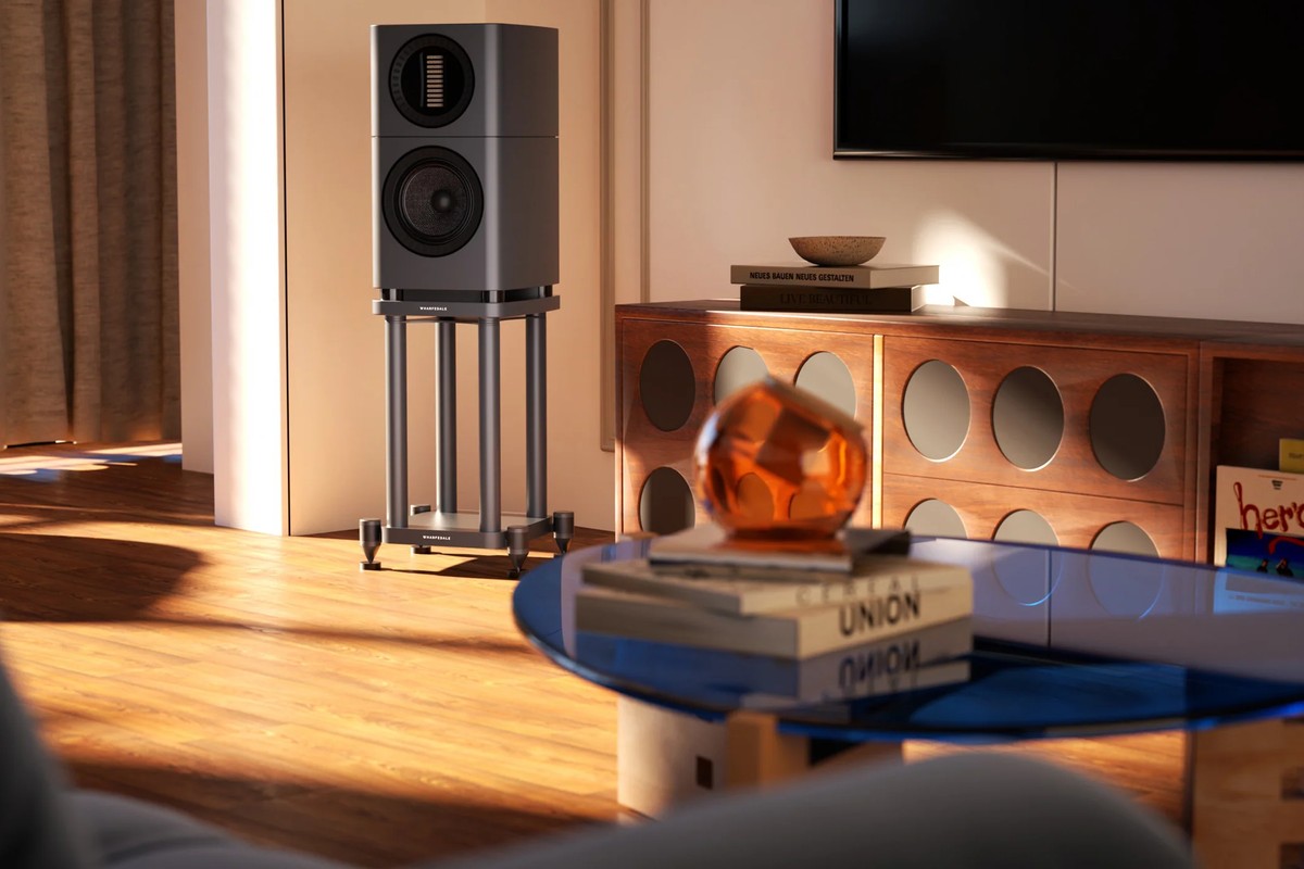 A speaker on a stand in a living room, next to a coffee table and a wooden cabinet