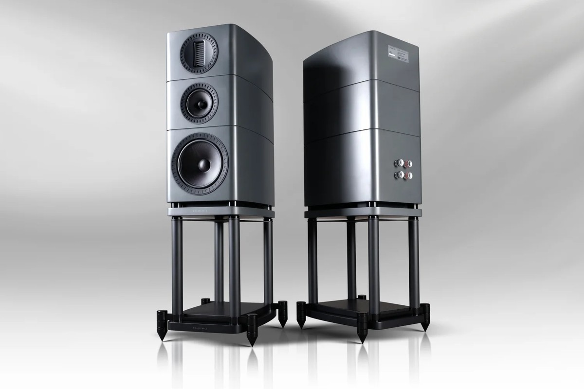 Two speakers on black stands, one from the front and the other from behind, on a light gradient background