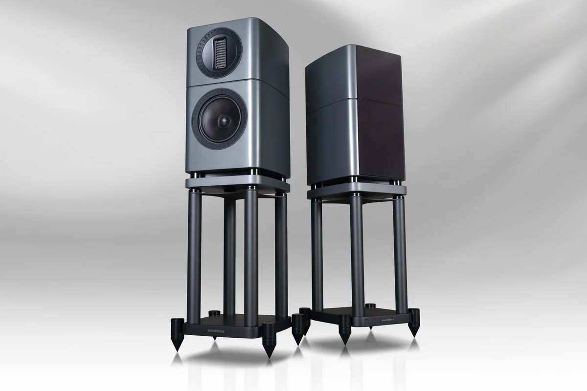 Two speakers on black stands, one from the front and the other from behind, on a light gradient background