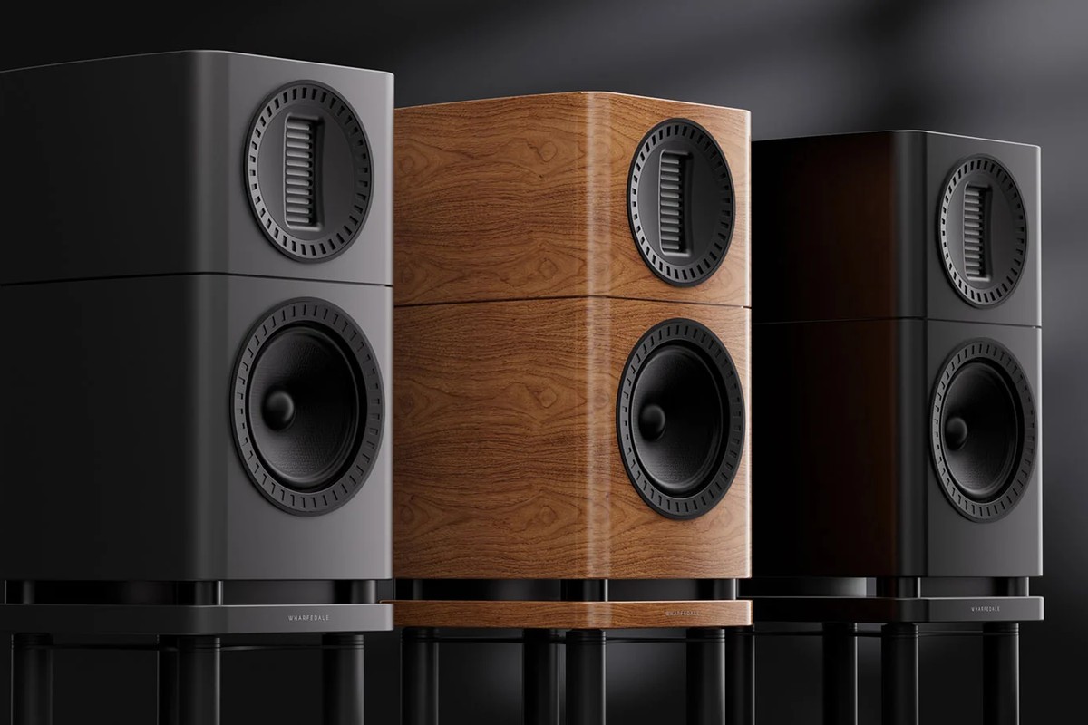 Three speakers in grey, light walnut and black on black stands