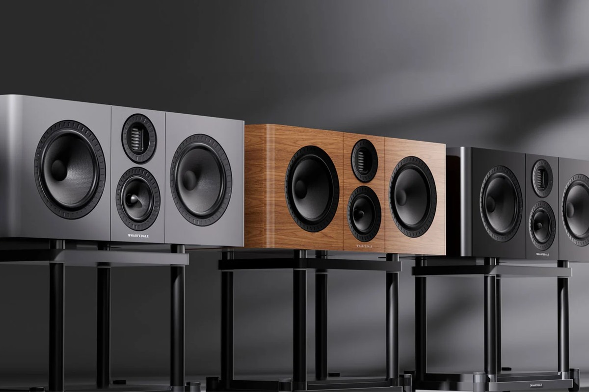 Three centre speakers in grey, light walnut and black, each on a black stand