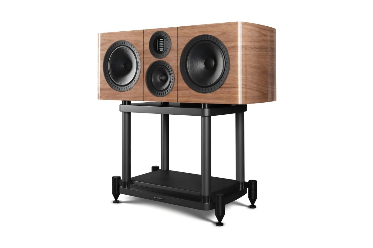 A light walnut centre speaker on a black stand, on a white background