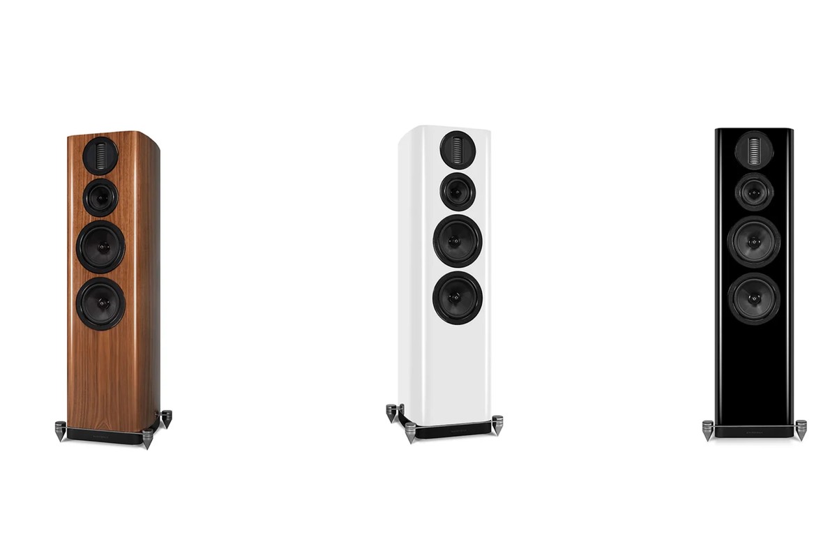 Trois enceintes colonnes en noyer, blanc brillant et noir brillant, vues de trois quarts sur fond blanc
