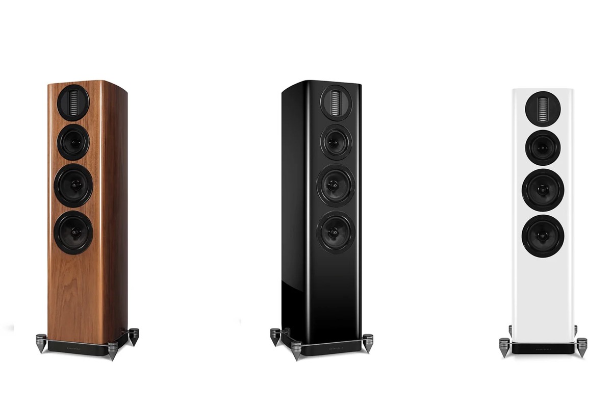 Three floorstanding speakers in walnut, hi-gloss black and hi-gloss white, seen from three-quarter angle on a white background