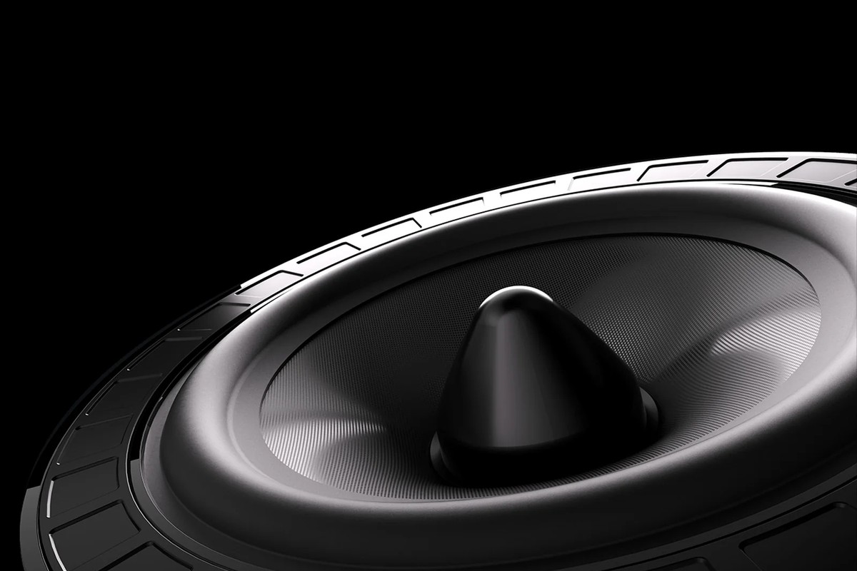 Close-up of a woofer with a black cone and rubber surround on a black background