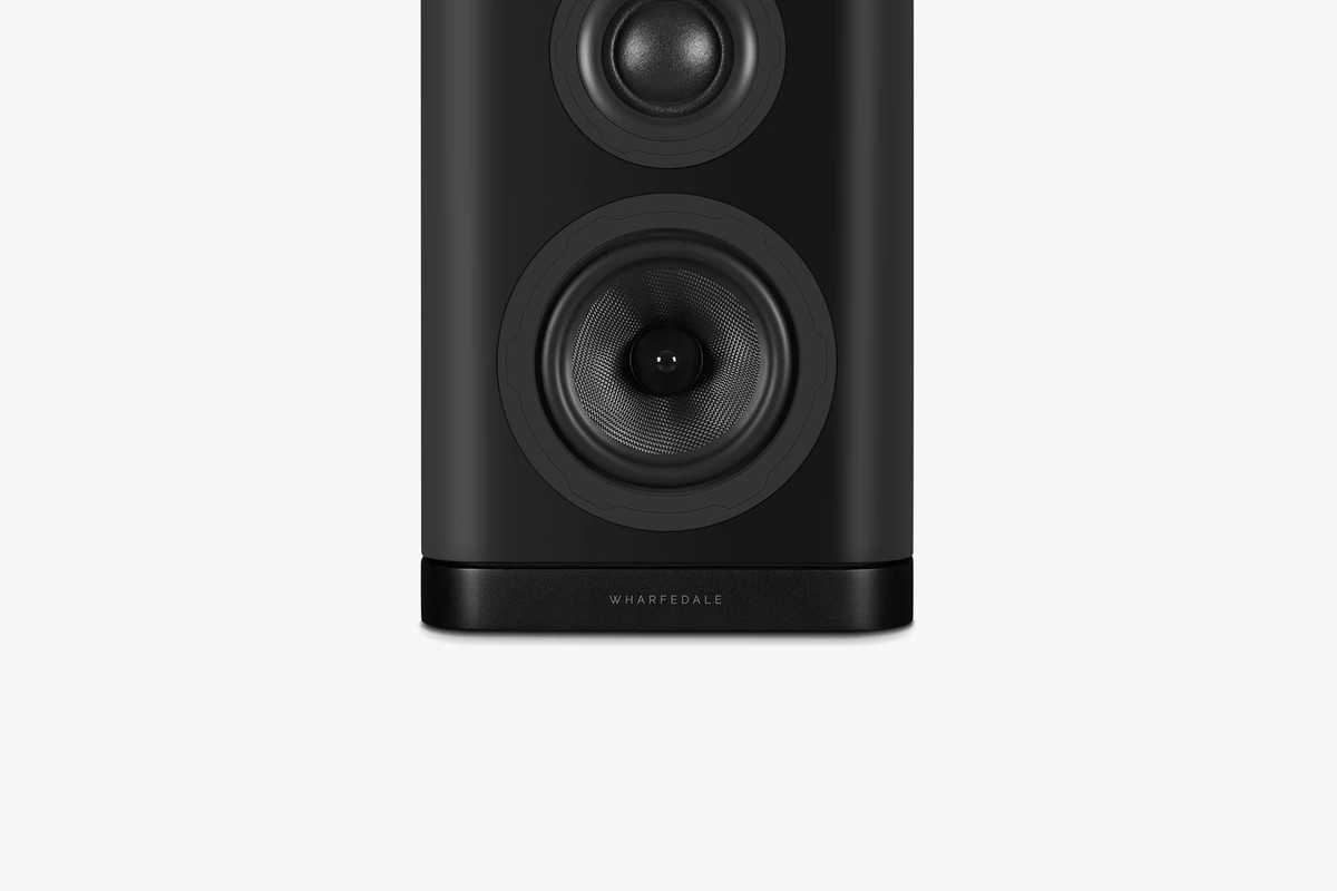 Front of a black bookshelf speaker, from the woofer down to its base
