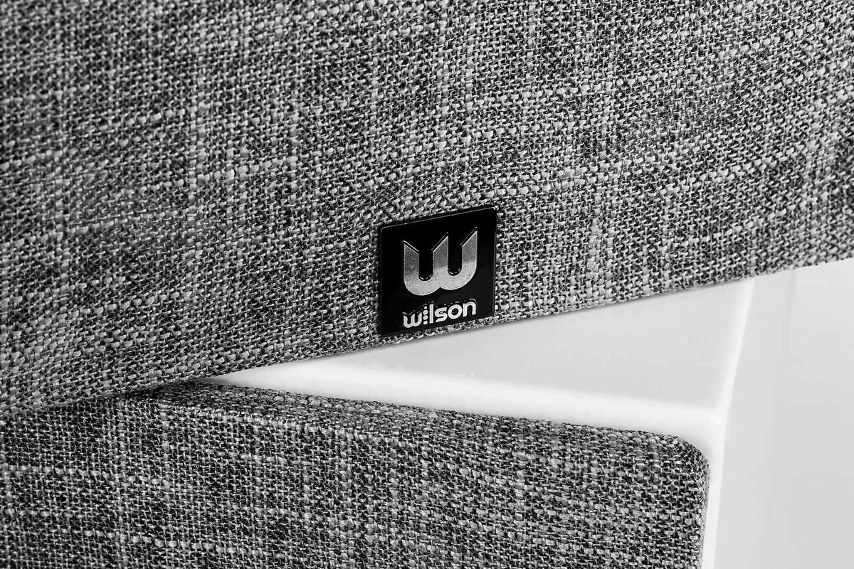 Frontgitter aus grau meliertem Stoff mit Wilson-Logo auf einem weiss lackierten Gehäuse