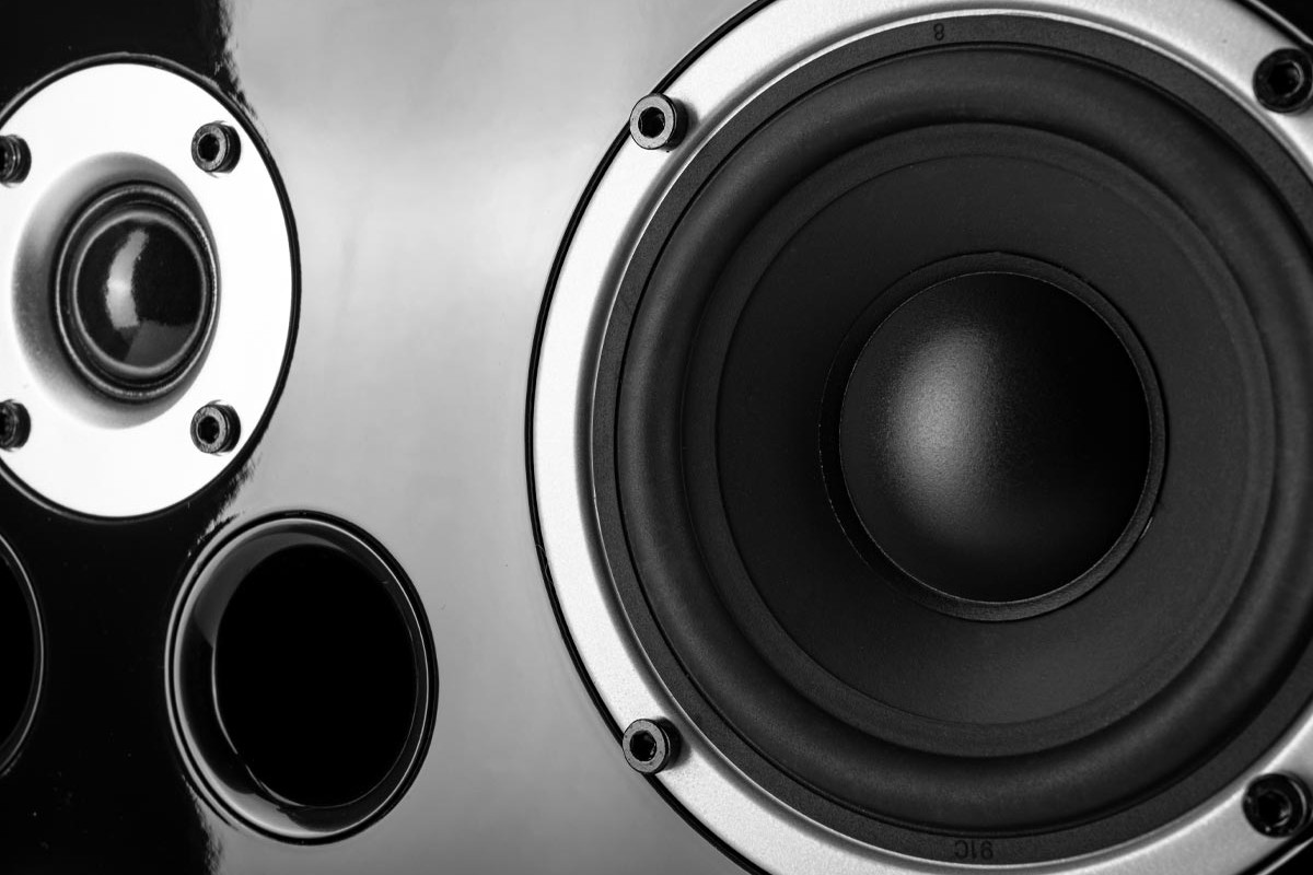 Close-up of the tweeter dome, a port and a black-cone driver on glossy lacquer