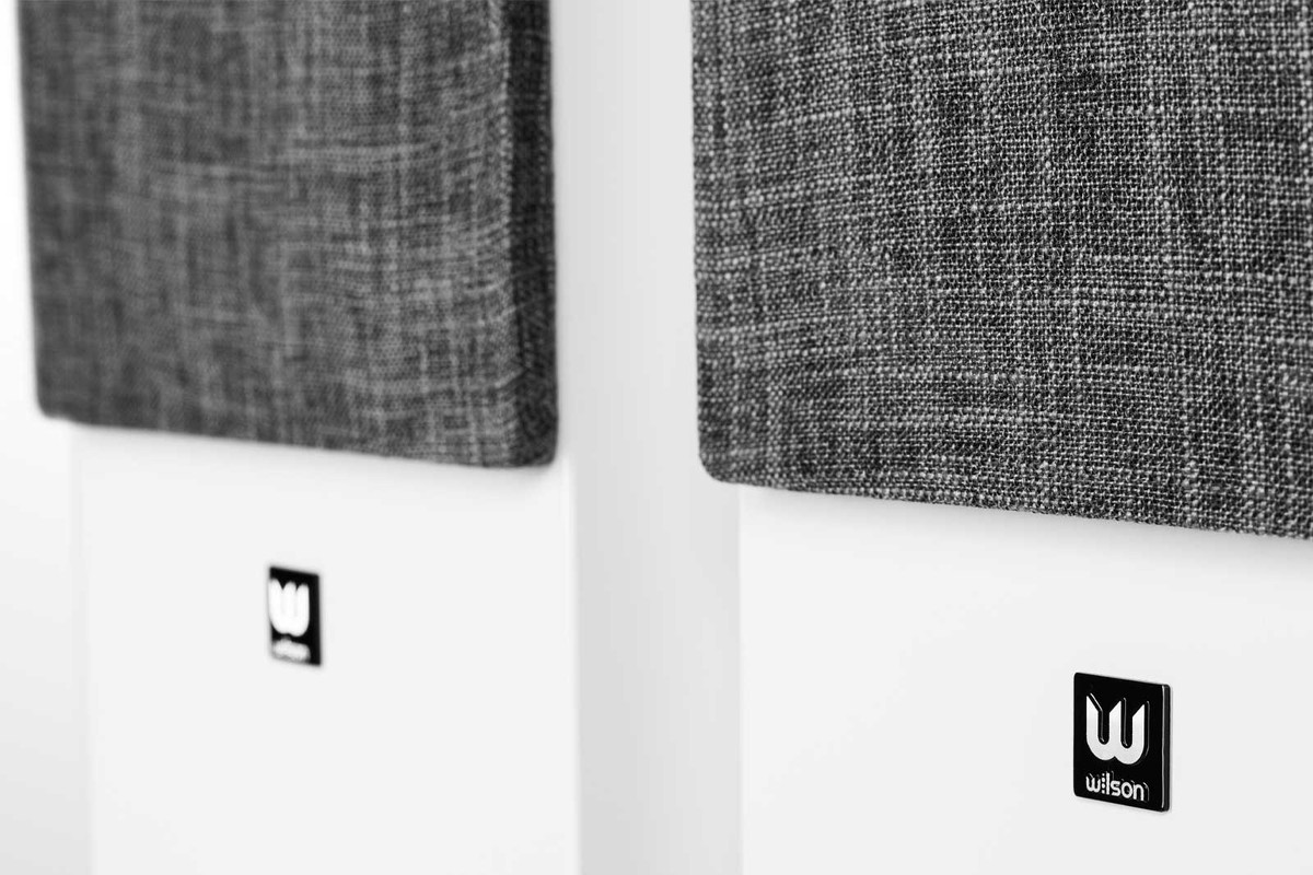 Gros plan sur deux grilles grises en tissu chiné posées sur des enceintes blanches