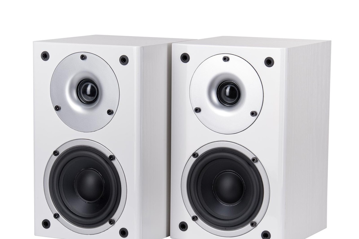 Pair of white bookshelf speakers seen from three quarters, dome and mid-range driver visible
