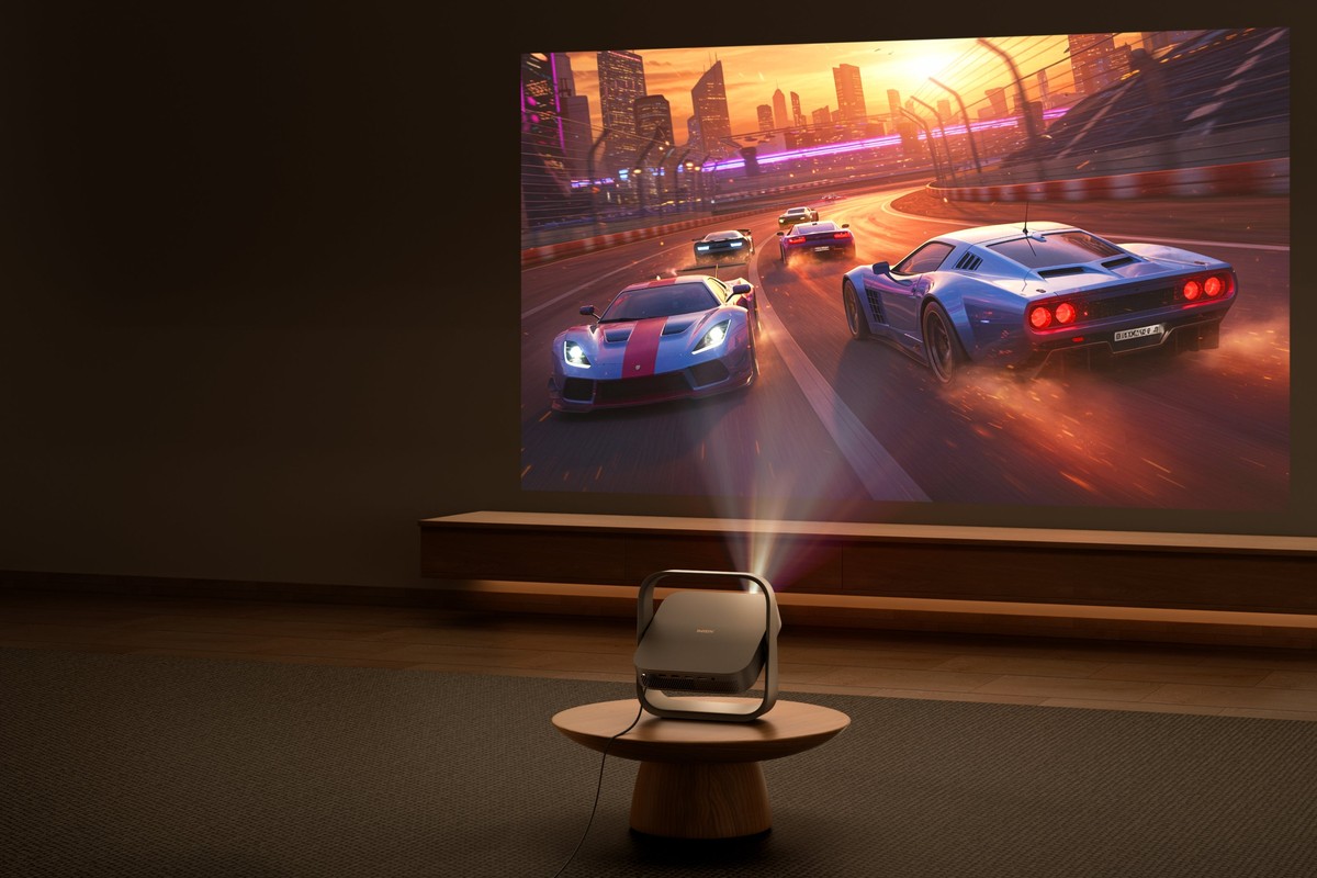 Course automobile projetée sur le mur d'un salon sombre, projecteur sur une table basse