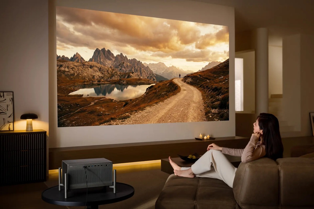 Frau auf einem Sofa vor einer wandfüllenden Berglandschaft