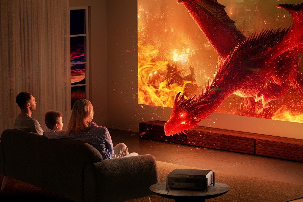 Famille assise dans un canapé face à un dragon de feu projeté sur tout le mur du salon