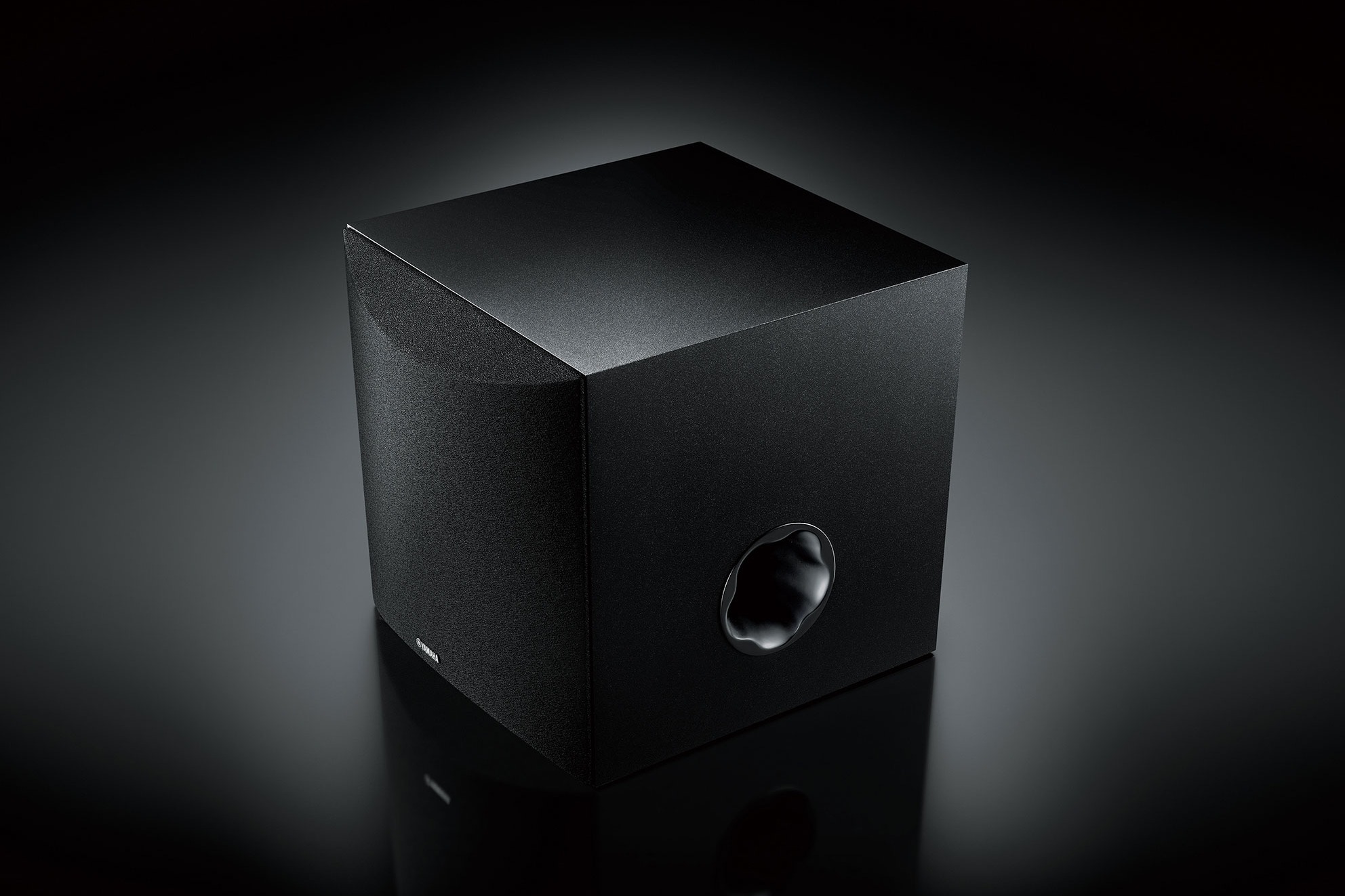 Black subwoofer shot against a dark background, front port visible