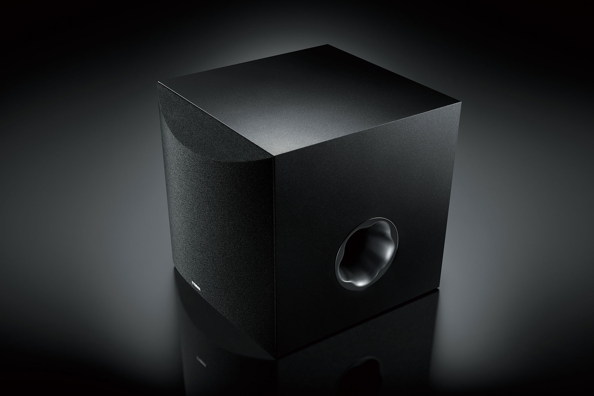 Schwarzer Subwoofer vor dunklem Hintergrund, Reflexrohr sichtbar