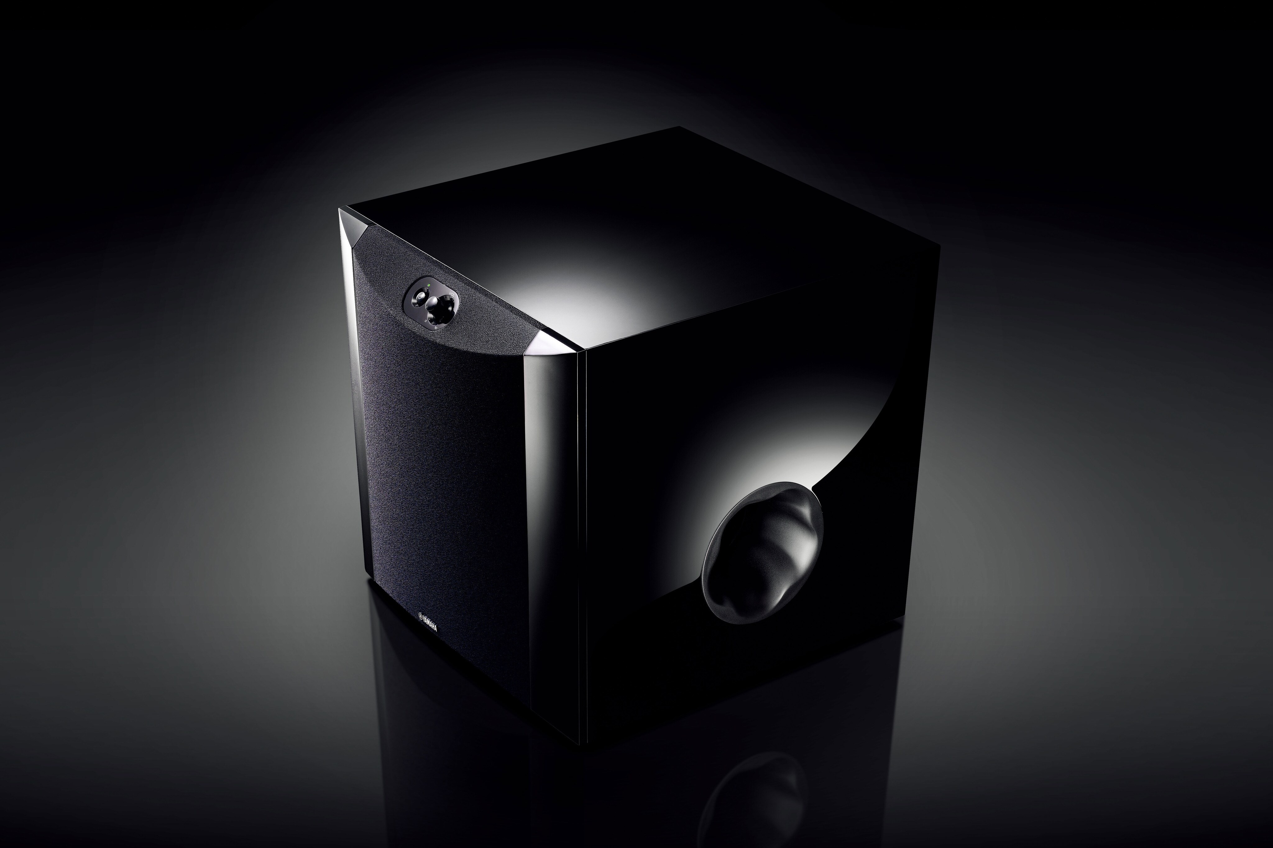 Black subwoofer shot against a dark background, front port visible