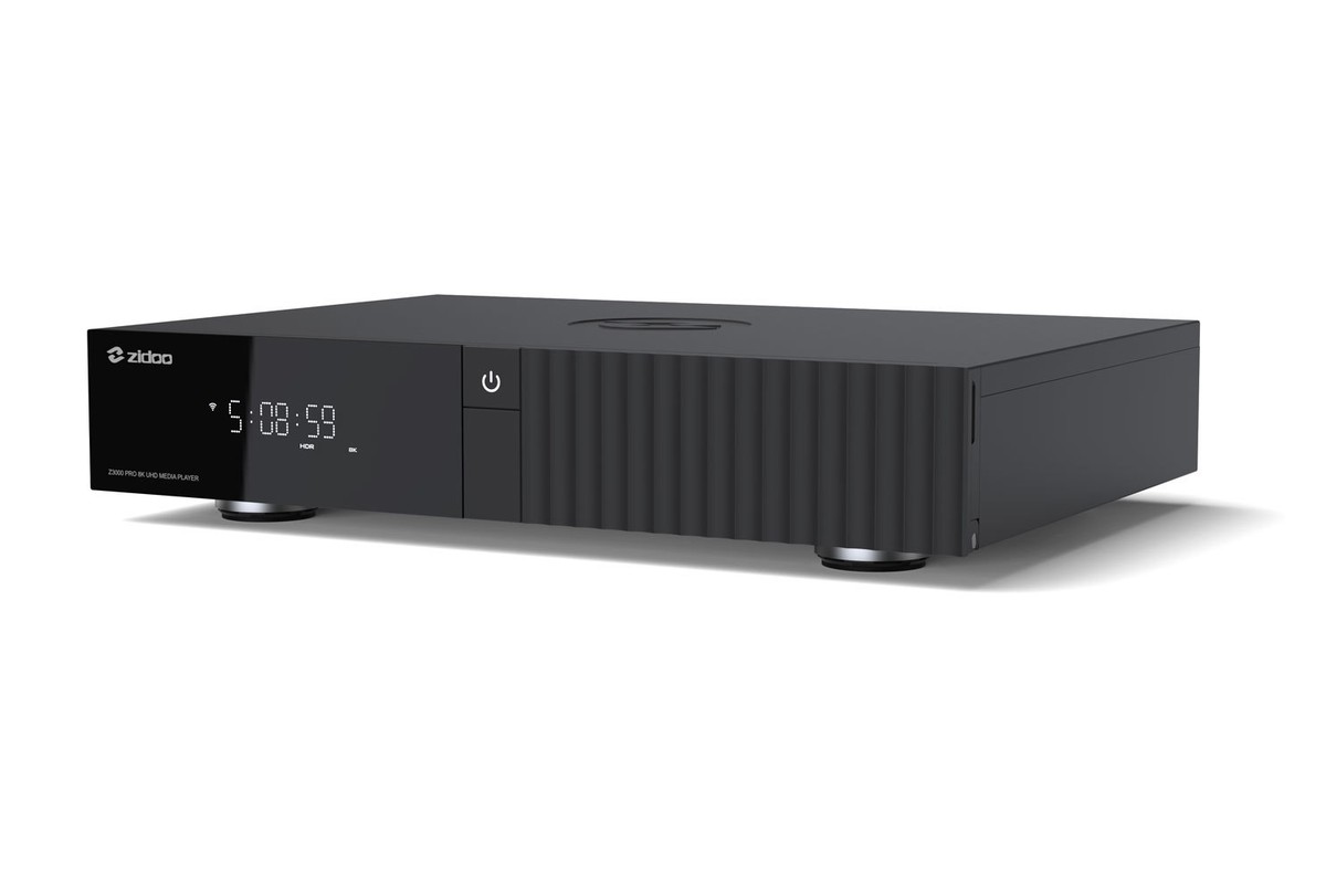 Black unit seen at three-quarter angle from the left, smooth top cover and metal feet