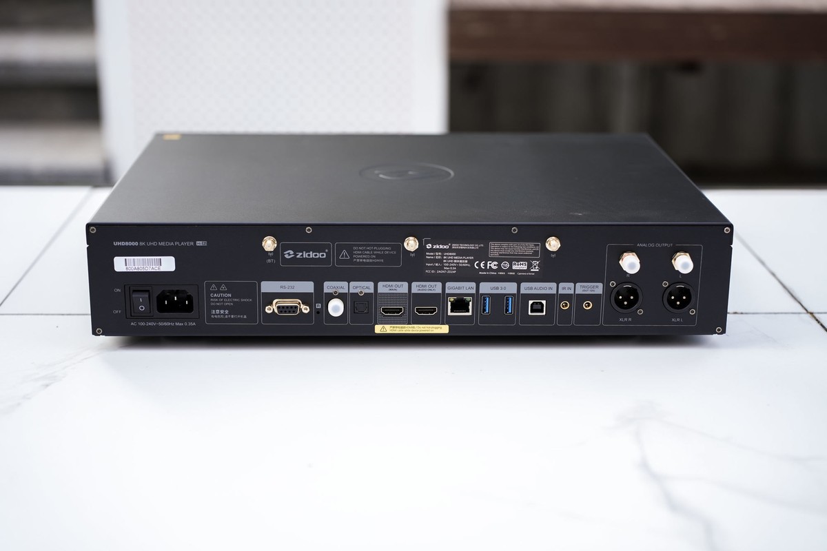 Face arrière photographiée sur un sol en marbre, prises XLR, HDMI, Ethernet, USB et connecteurs d'antenne