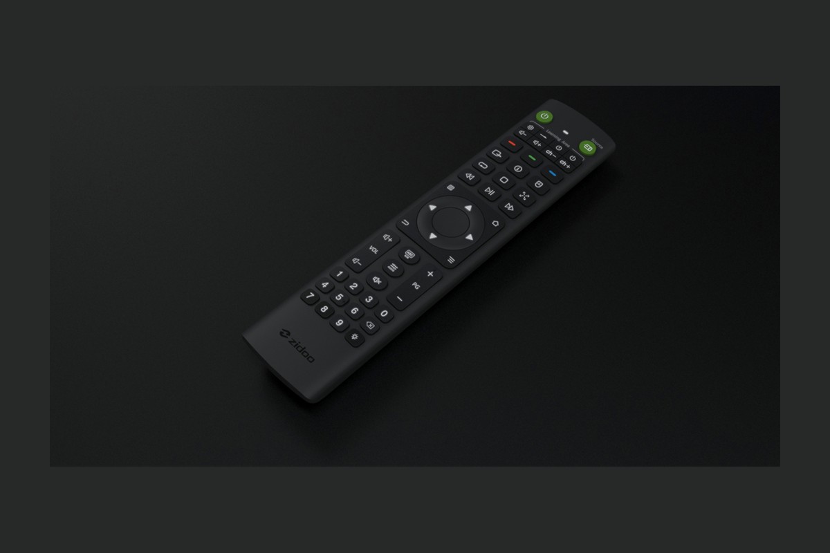 Télécommande noire posée en biais sur un fond sombre, pavé directionnel et clavier visibles