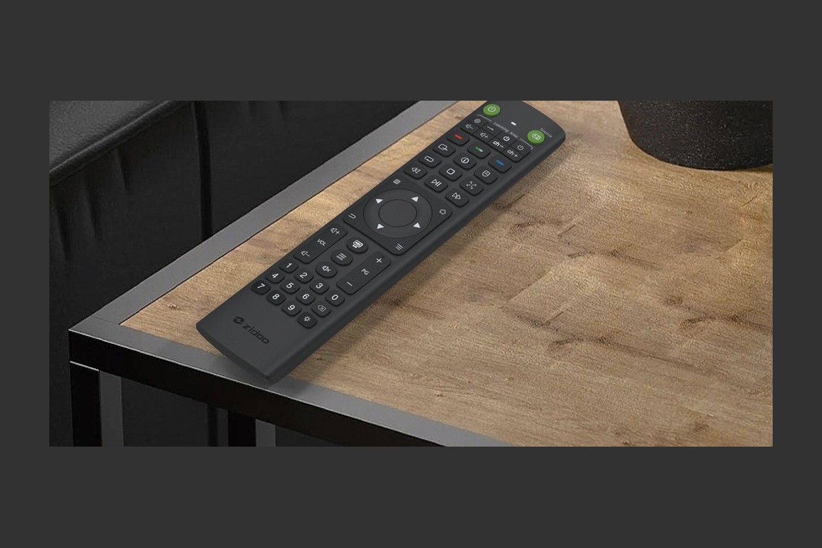 Télécommande noire à touches vertes posée sur une table basse en bois et métal